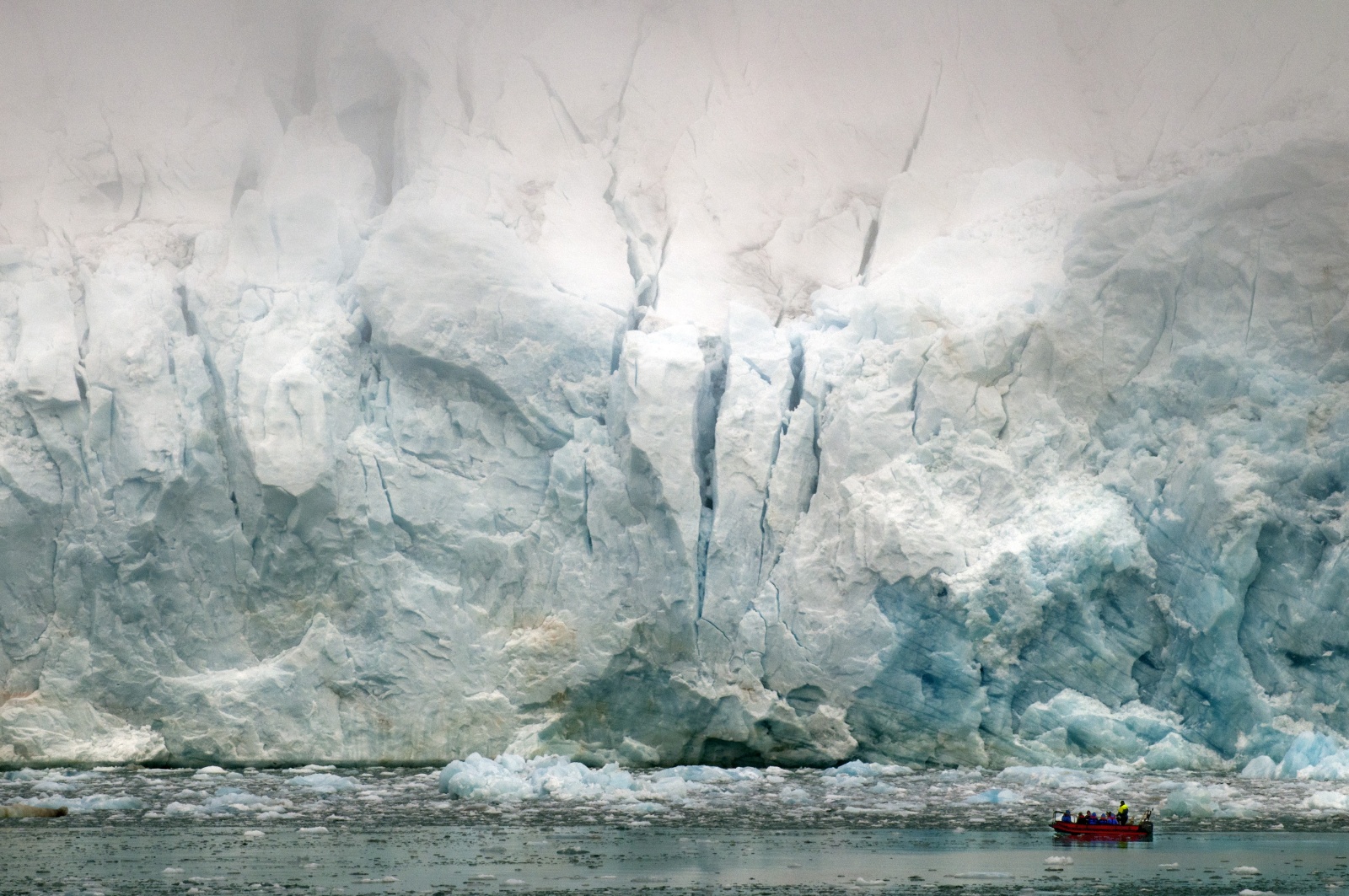 Lacerazioni Polari - Il ghiacciaio si butta nel mare e cadono blocchi con grande fragore dalla sommità nascosta nella nebbia. Un gruppo di visitatori si avvicina in gommone...l'uomo è veramente piccolo di fronte alla natura 