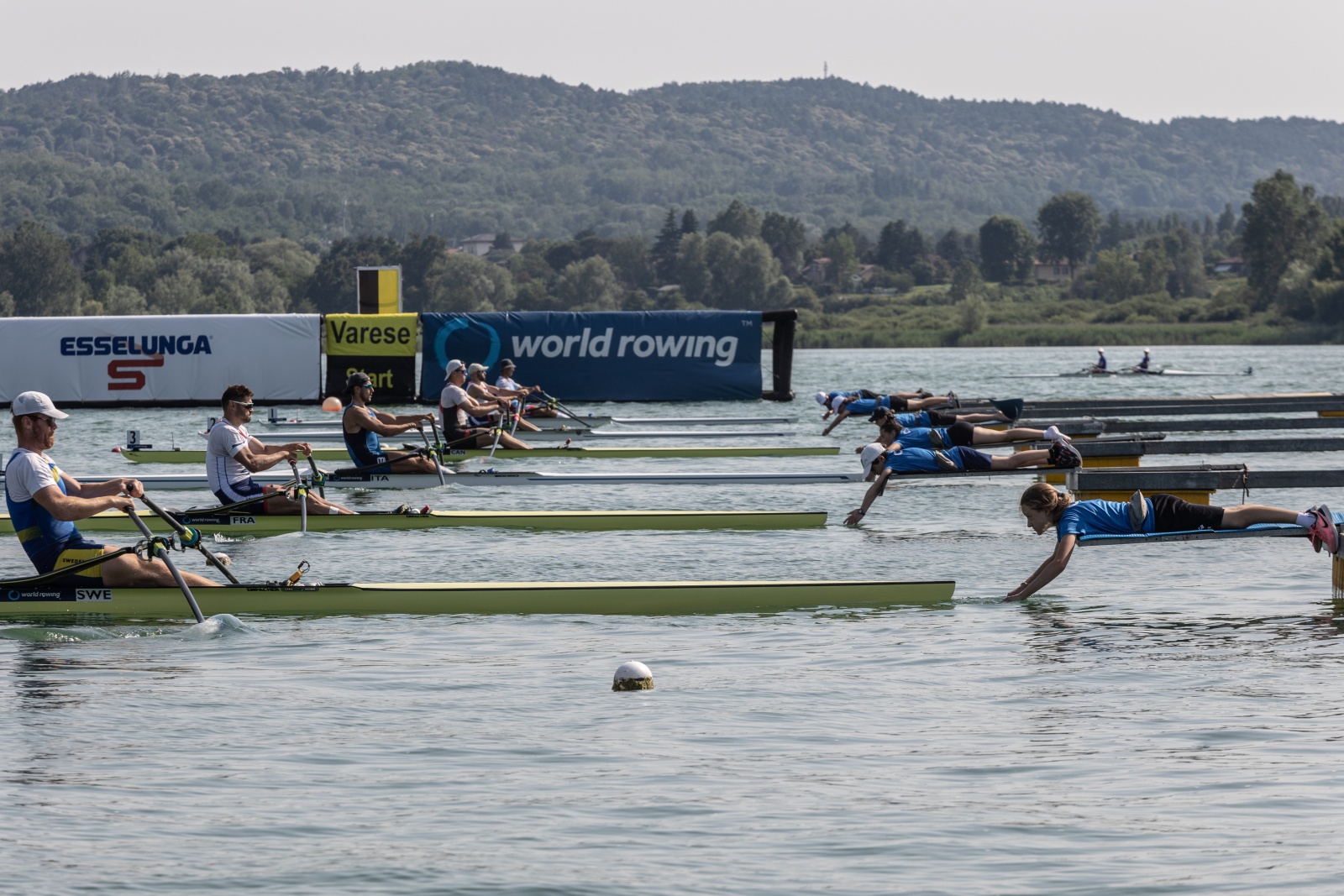 VARESE, ITALY - JUNE 16: At the starts of World Rowing  Cup II on the first day, volunteers lying on the pontoons hold the hulls of the rowing boats until the starting siren sounds in Varese, Italy, on June 16, 2023.